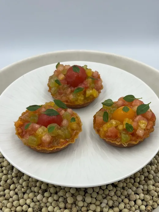 Trois tartelettes à la tomate et au basilic, sur une assiette blanche