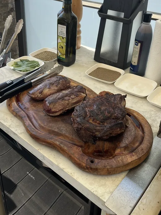 Deux magrets de canard et une pièce de bœuf grillée sur une planche en bois